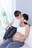 Pregnant woman with son kissing forehead
