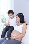 Pregnant woman with son reading book