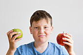 Boy holding red and green apple