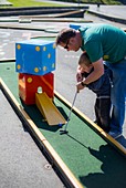Father helping son to play mini golf