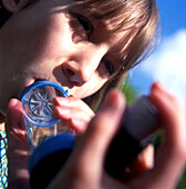 Girl with asthma uses an inhaler adaptor outdoors