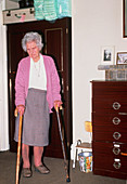Arthritic elderly woman walks with walking sticks