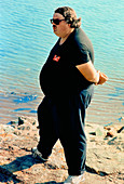 Obese man stands by water