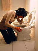 Bulimia: young woman trying to vomit at a toilet