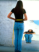 Anorexic teenage girl measuring herself in mirror