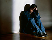 Depressed teenage girl sits on the floor indoors