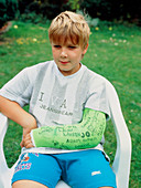 Boy sits with arm im plaster for broken wrist