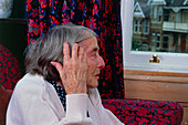 Loneliness: elderly woman staring out of window