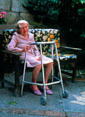 Elderly woman with walking frame resting in garden
