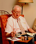 Elderly man with prescription drugs on table