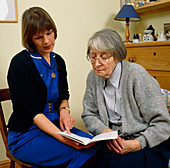 District nurse shows information book to old woman