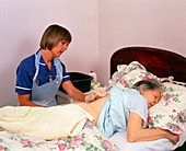District nurse gives elderly patient a bed bath