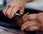 Elderly woman peeling potatoes