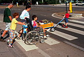 Boy in wheelchair crossing road with family