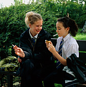 Young teenage girls lighting cigarettes outdoors