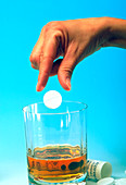 Woman's hand dropping pill into an alcoholic drink