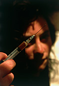 Addict holding syringe containing heroin