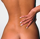 Back pain: woman's hand held to her lower back
