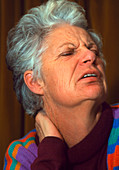 Elderly woman holds her neck in expression of pain