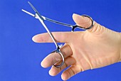 Gloved hand holding a pair of scissor forceps