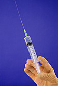 Gloved hand gently squeezing a syringe