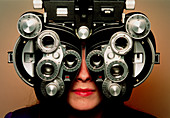 Eye examination: woman looks through a refractor