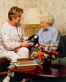 Nurse takes the blood pressure of an elderly woman