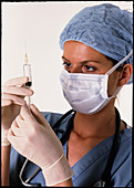 Masked female anaesthetist prepares a syringe