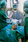 Medical staff monitor a woman after breast surgery