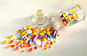 Coloured assortment of pills spilling from bottle