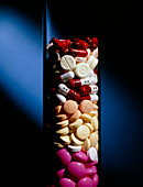 Assorted pills and drug capsules in glass cylinder