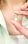 Woman holding a drug capsule