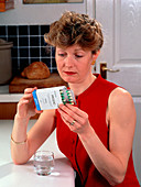 Woman reading dose label on pack of Prozac pills