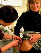 Nurse giving a young woman gamma-globulin vaccine