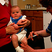 Nurse administering vaccine into leg of young baby