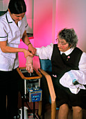 Woman undergoing wax bath treatment for arthritis