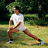 Athletic man doing leg stretch exercise outdoors