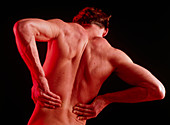 Young man affected by back pain doing self-massage