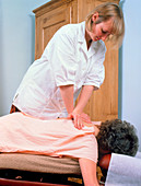Chiropractor presses on spine of a woman patient