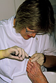 Chiropodist cuts the toenails of elderly patient