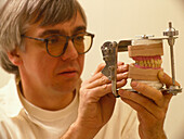 Dental technician with set of false teeth