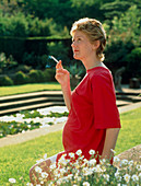 Pregnant woman smoking a cigarette outdoors
