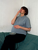 Pregnant woman smoking a cigarette indoors