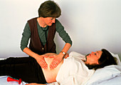 Doctor palpates a pregnant woman's abdomen
