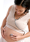 Pregnant woman using a stethoscope