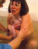 Water birth: mother holds her newborn baby