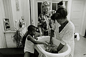 District maternity nurse watches mother bathe baby