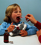 Child receiving a dose of cough mixture