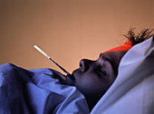 Child in bed with flu,thermometer