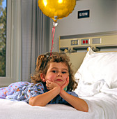 Sad young girl on a bed in a paediatric ward